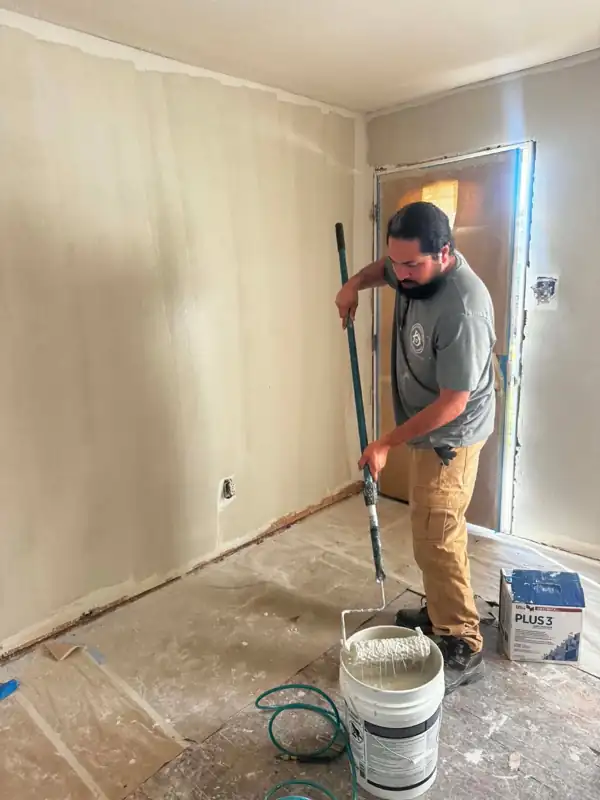 Davis crew member rolling primer on a wall
