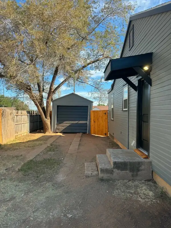 Updated gray siding with new black door awning and cedar gate